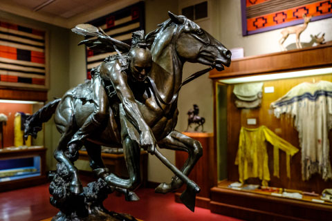 A sculpture of a Native American riding a horse