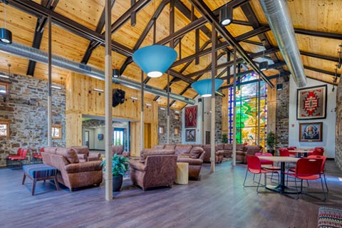 Woolaroc Welcome Center main hall with view of seating area, open ceiling, and stained glass window